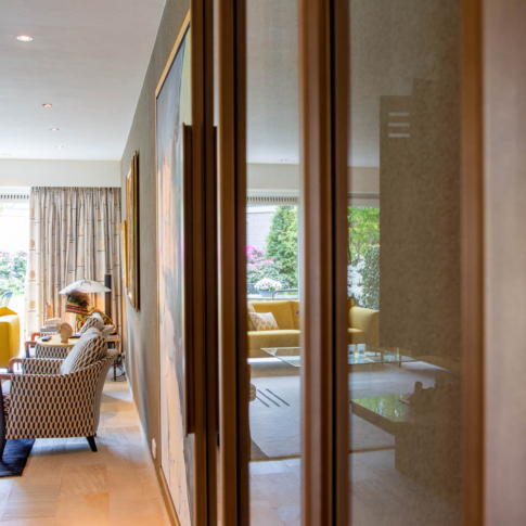 Bronzen stalen taatsdeur met glas in een luxe interieur met kunst en warme tinten.